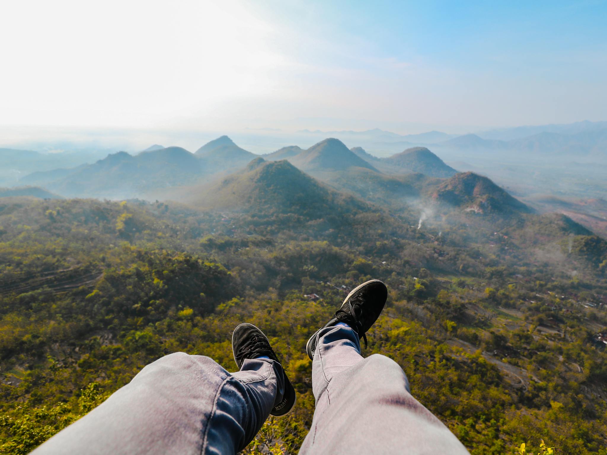Feet dangling over the stunning landscape of Wonogiri Hills during sunrise, capturing the essence of Indonesian nature.